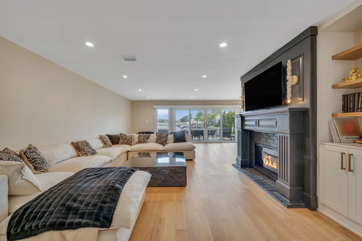 Open-concept living area with fireplace and floating shelves in Islip, NY condo remodel by Kuhn Construction