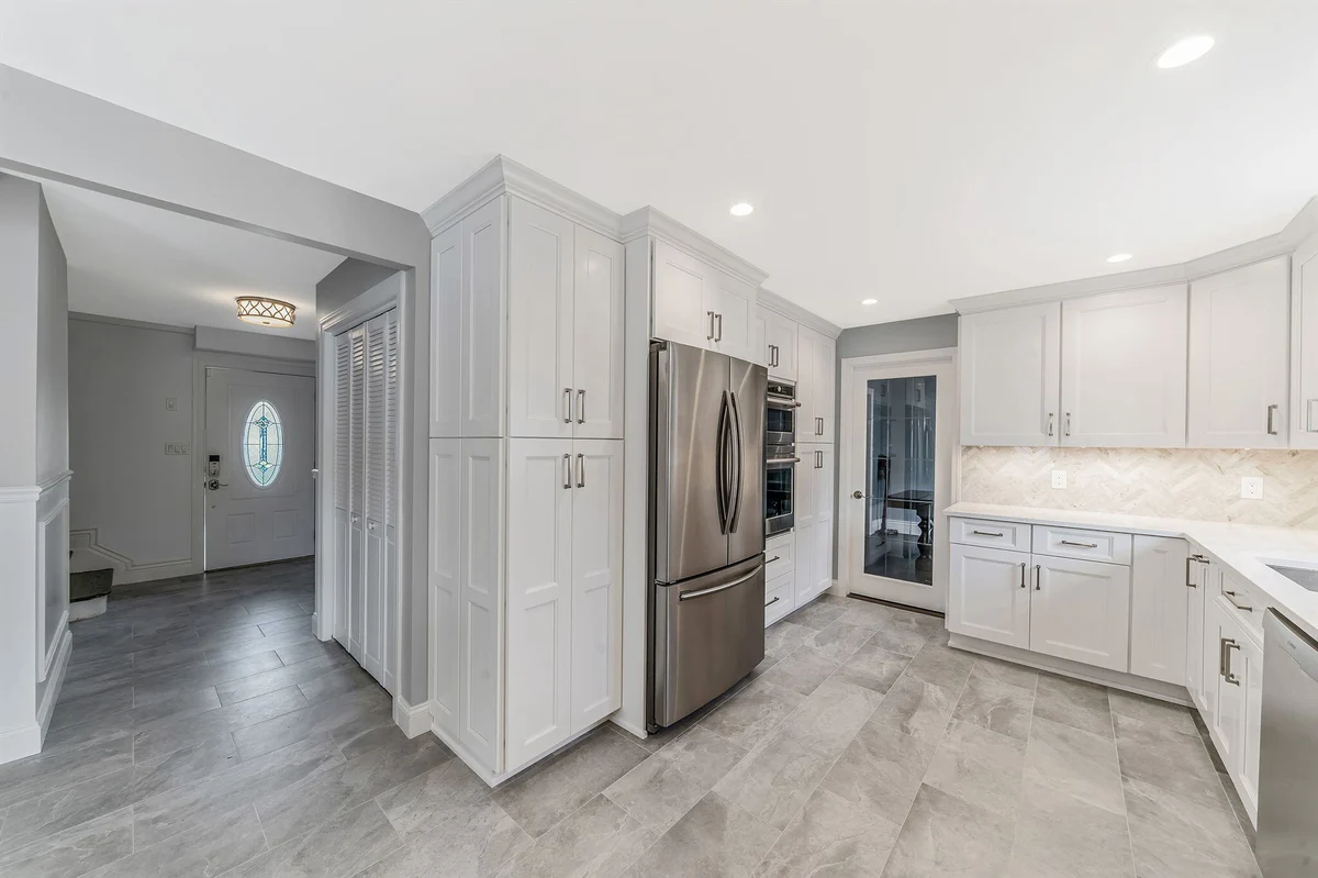 Massapequa kitchen remodel by Kuhn Construction showcasing Fabuwood white cabinetry and stainless steel fridge